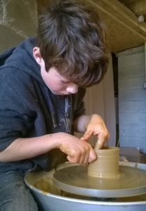 Pratique du tour de poterie par un enfant à  l'atelier d'Autrans